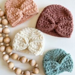 Four crocheted Star Stitch Crochet Baby Hats with wooden beads on them.