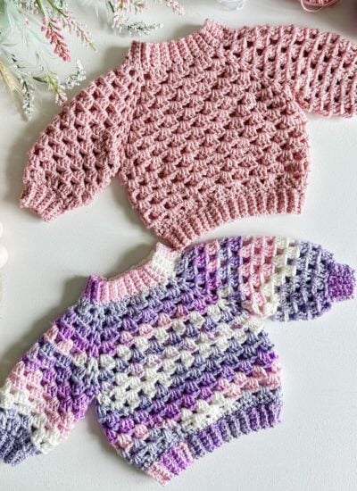 Two top-down crocheted sweaters on a white table.