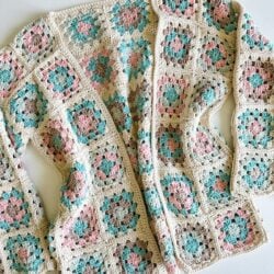 A Granny Square Cardigan adorned with pink, blue, and green flowers.