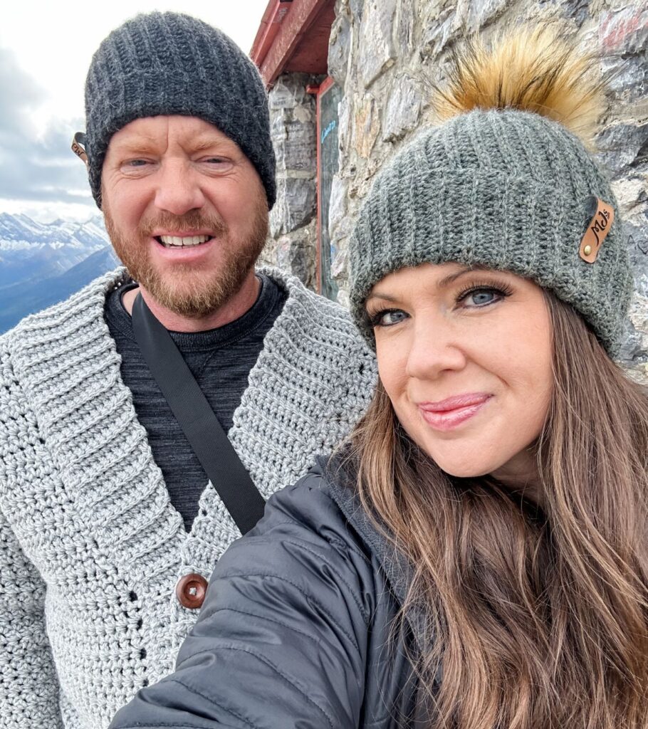 A man and woman wearing Rocky Ridge Crochet Hats taking a selfie at the top of a mountain.