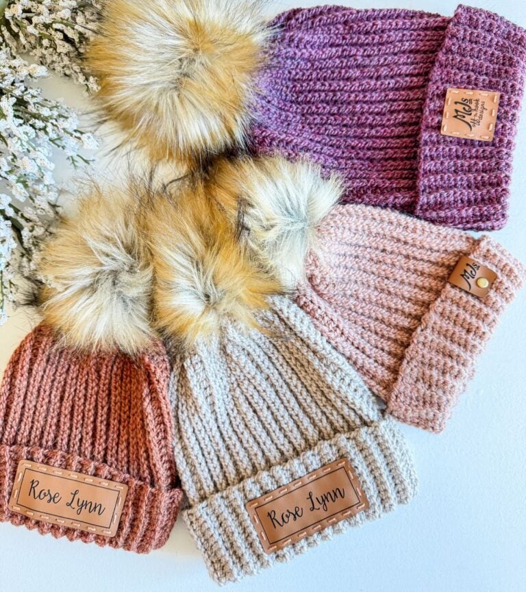 Four crochet hats with pom poms on them.