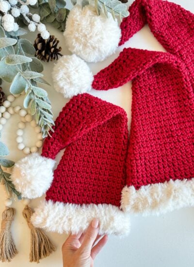 Two crocheted Santa hats with pom poms, perfect for holiday festivities.