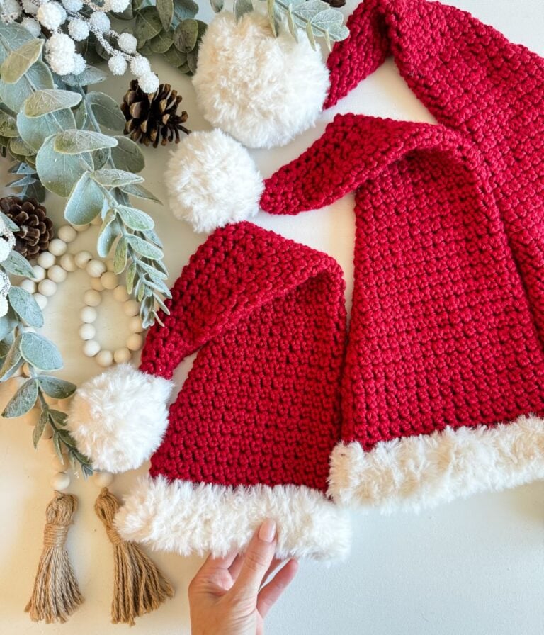 Two crocheted Santa hats with pom poms, perfect for holiday festivities.