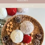 A woven basket filled with three Christmas Crochet Ornaments, pinecones, wooden beads, and balls of yarn in white, red, and cream on a white surface.