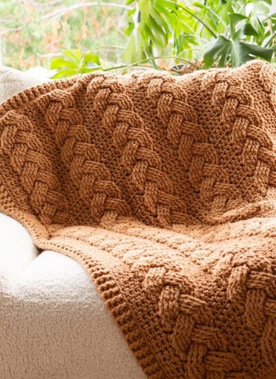 A brown cabled throw blanket on a chair.