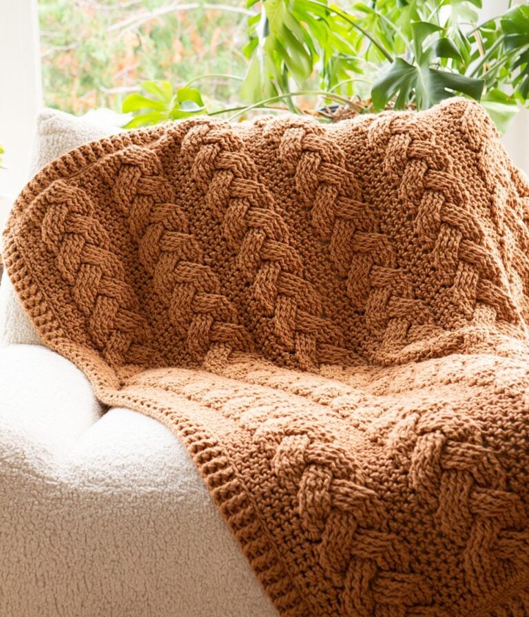 A brown cabled throw blanket on a chair.