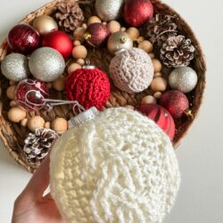 A person holding a Christmas crochet ornament.