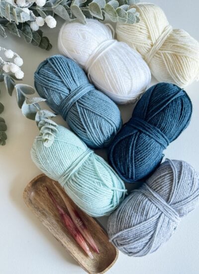 Four balls of yarn on a white table, perfect for knitting a cabled hat.