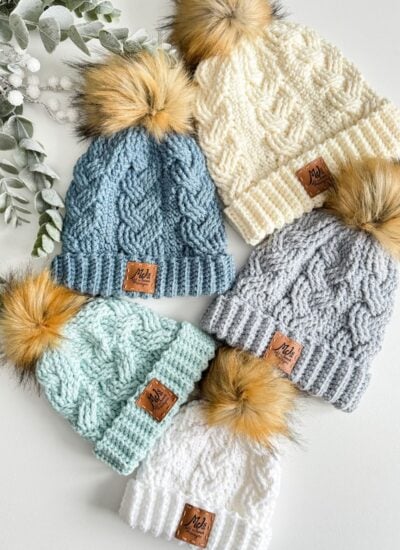 Four cabled hats with pom poms.