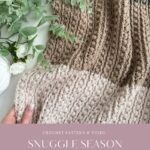 A hand holds a textured, striped crochet blanket in neutral colors, surrounded by greenery, with text reading "Snuggle Season Blanket" and a charming granny square ornament nearby. Website link appears at the bottom.
