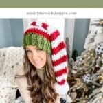 Woman wearing a crocheted red, white, and green elf hat sits on a couch by a decorated Christmas tree with a granny square ornament. Text above reads "Elf Hat Crochet Pattern & Video.