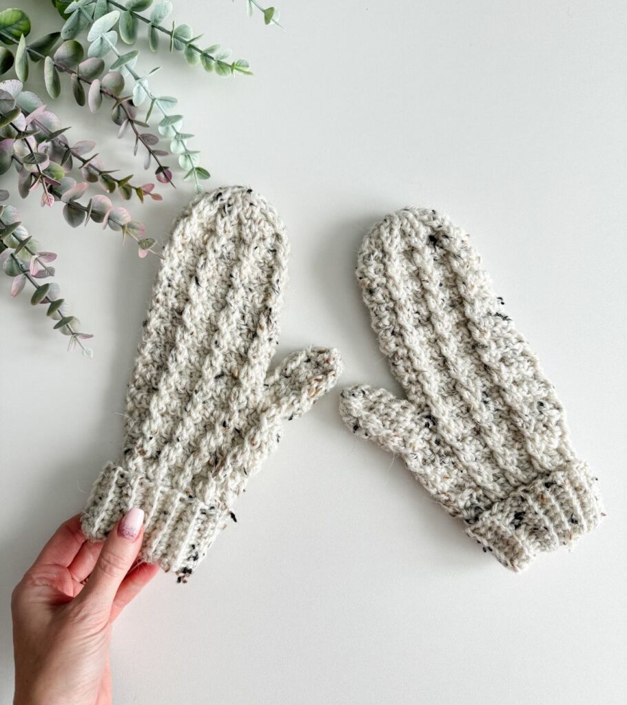 Two crocheted mittens on top of a table.