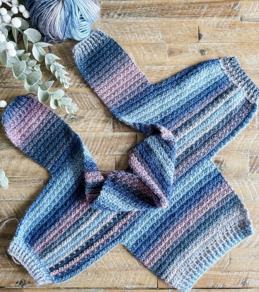 A blue and pink cardigan on a wooden table.