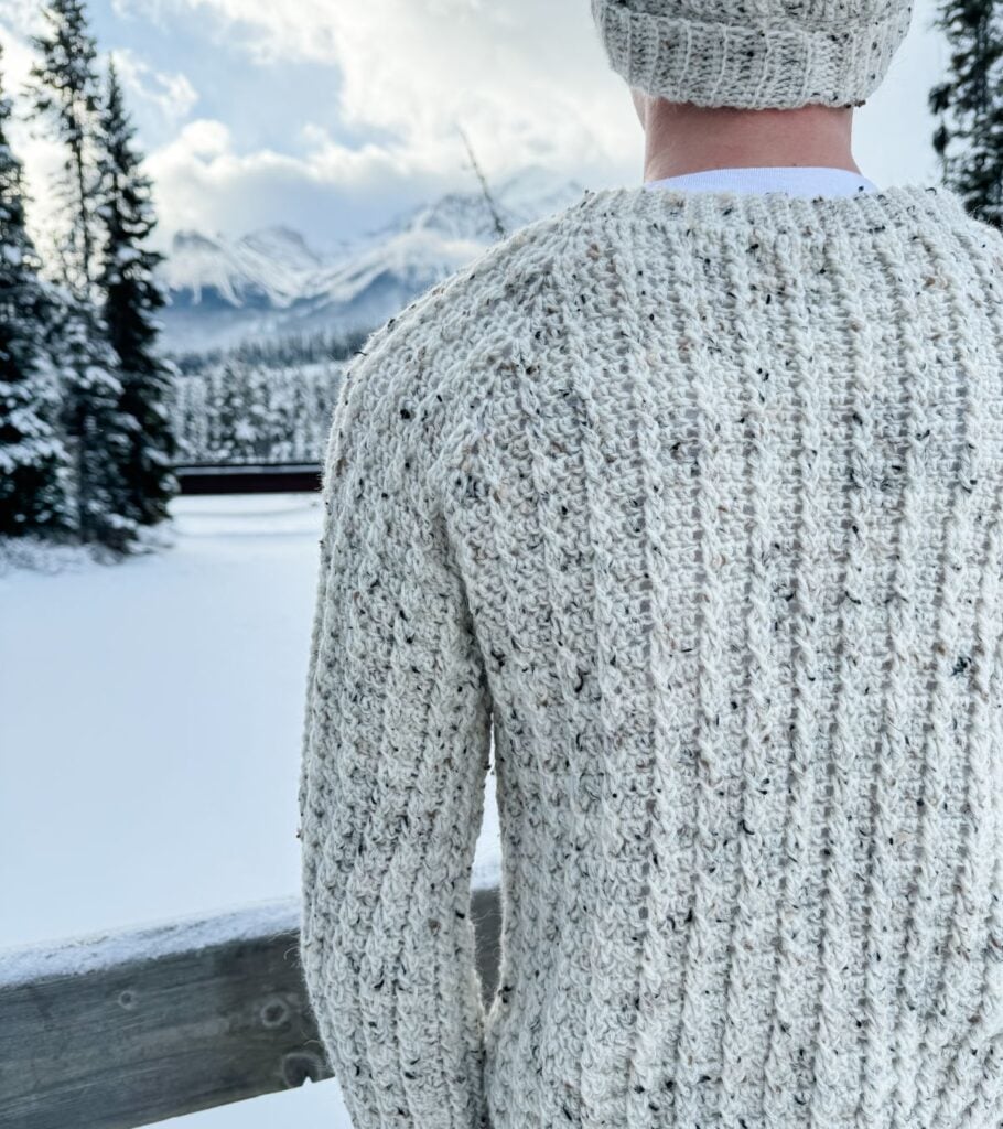 A man wearing a crochet hat in the snow.