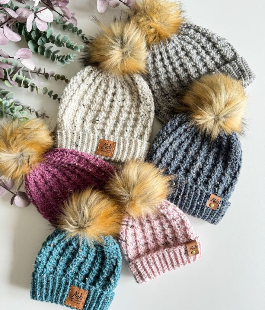 A group of crocheted hats with pom poms.