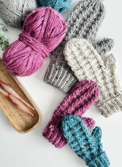 Crochet mittens with yarn on a table.