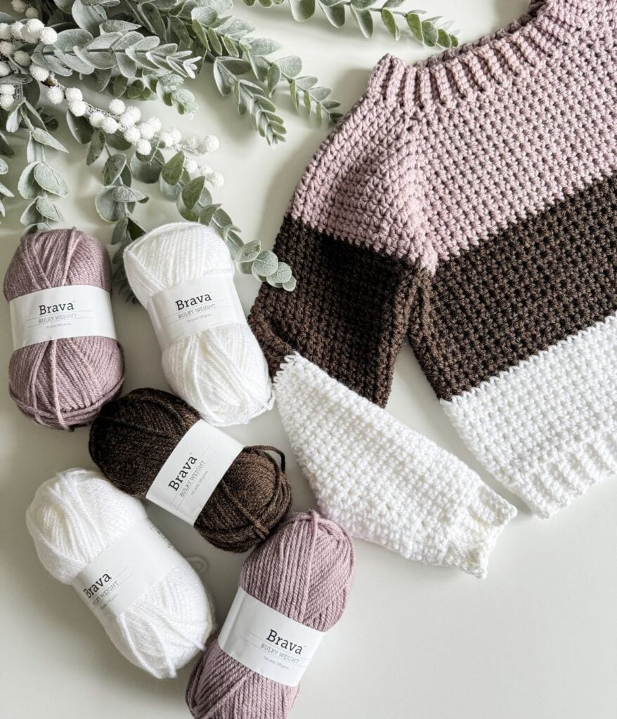 A children's pullover knitted with pink, white, and brown yarn.