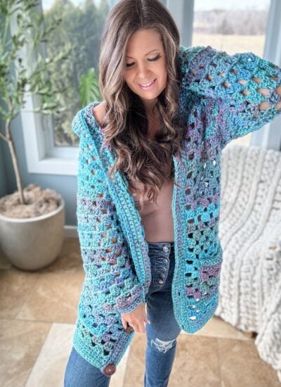 A woman wearing a crochet pullover and jeans.