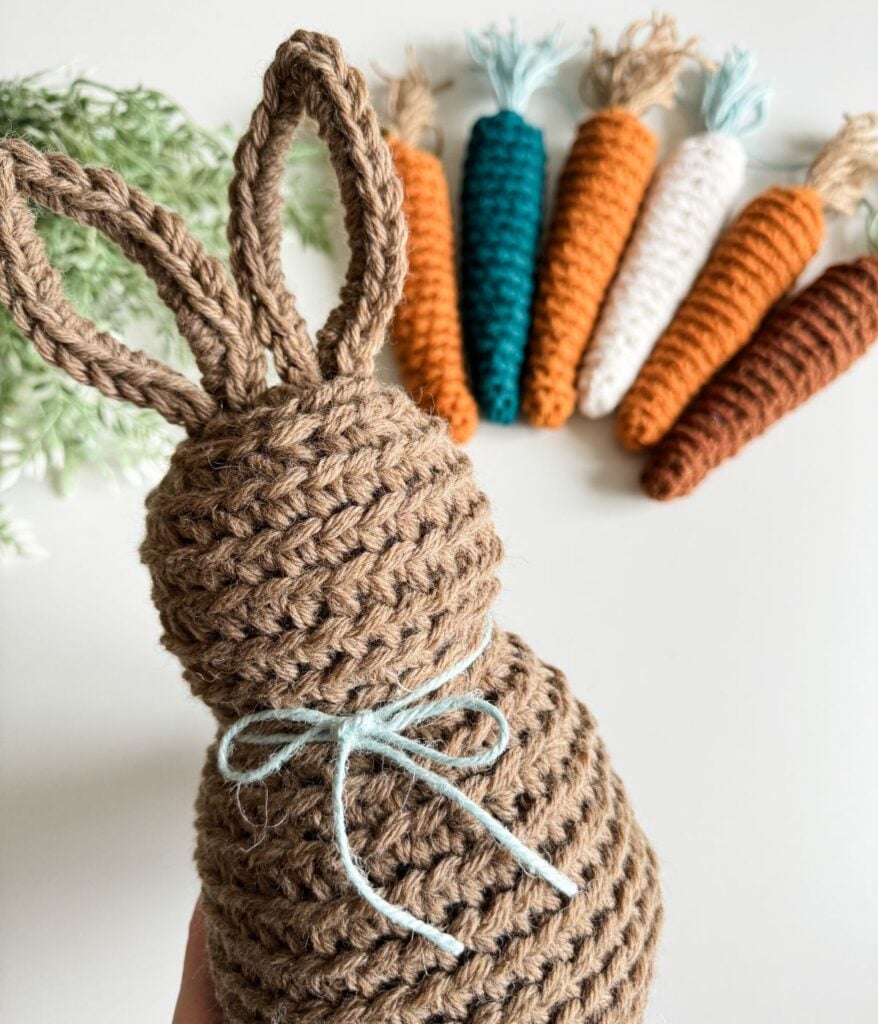 A crochet bunny pattern with carrots in front of it.