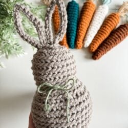 A crocheted bunny pattern with carrots in front of it.