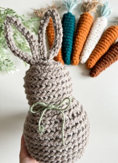 A crocheted bunny pattern with carrots in front of it.