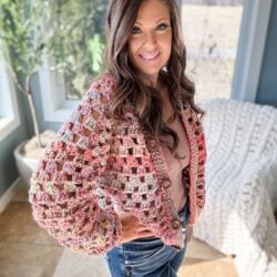 A woman wearing ripped jeans and a crocheted pullover.