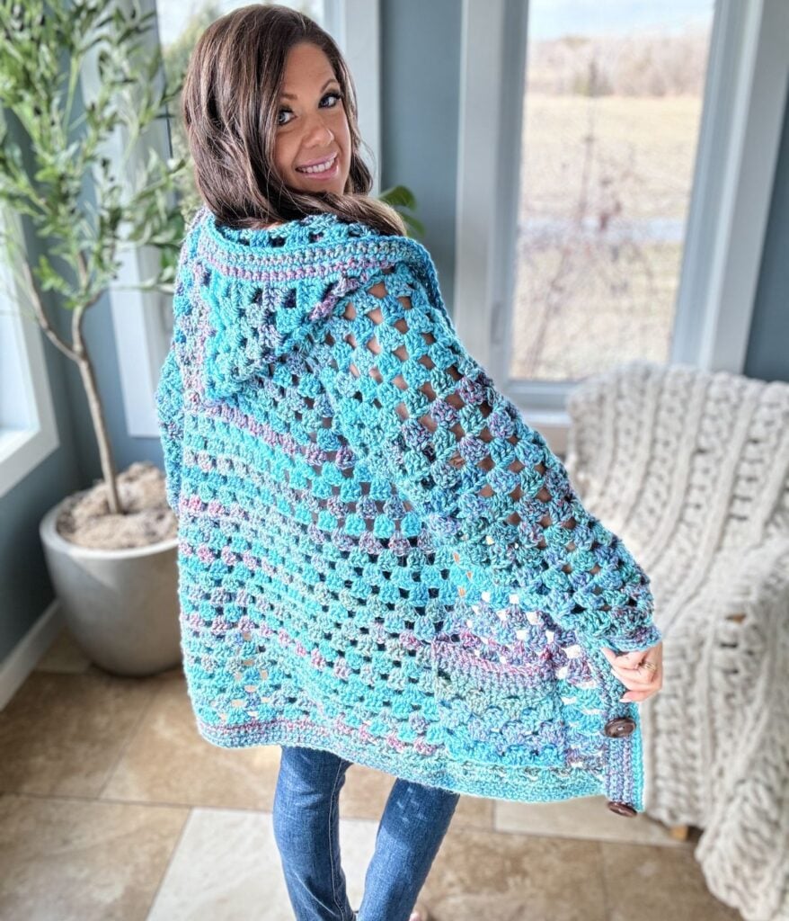 A woman wearing a blue crochet pullover in a living room.