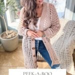 The woman is elegantly styled in a textured, long, light pink crochet cardigan layered over a white top and jeans. She stands indoors by a potted plant. Caption reads "Peek-a-Boo Cardigan Crochet Pattern & Video Sizes XS-5X", perfect for pairing with your favorite crochet mesh top.