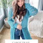 Woman wearing a blue crocheted cardigan with crochet mesh top details over a white shirt and jeans, standing indoors by a window. Text at bottom reads: "CABOT TRAIL CARDIGAN Crochet Pattern & Video Sizes XS-5X.