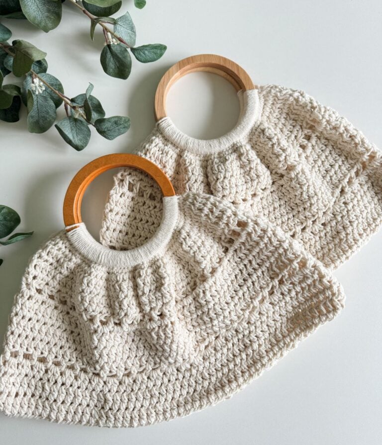 Two knitted handbags with wooden handles on a white surface, decorated with green leaves, showcasing a free pattern.