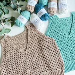 Two crochet tank tops in beige and teal are displayed with several skeins of yarn in coordinating colors. Green leaves are to the left. The yarn labels read "Comfy." Follow a free crochet pattern featuring the granny stitch for an effortlessly stylish look.