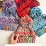 Four colorful Granny Stitch Hats with pom-poms are displayed on a white surface, each featuring a leather tag. A hand holds the front hat. Pinecones are in the corner. Text reads "Granny Stitch Hat.