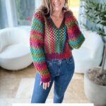 A person wearing a colorful granny stitch crochet pullover poses indoors with large windows in the background. Text reads "Granny Stitch Crochet Pullover Pattern, Sizes XS-5X + Video.