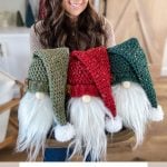A person holding three crochet gnome decorations with green, red, and dark green hats. Text reads: "Rustic Farmhouse Holiday Gnome Crochet Pattern & Video.