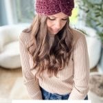 Woman wearing a crochet headband, sitting in a room with a white chair and plant. Text reads: "Puff Post Stitch Headband Pattern & Video. Baby - Adult Sizes.