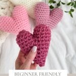 Hand holding a burgundy crochet heart, with pink and white hearts in the background. Text reads: "Beginner Friendly Bulky & Quick Crochet Heart Pattern & Video".