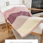 Crocheted blanket in shades of pink and cream draped over a wooden chair by the fireplace. Text reads: "Snuggle Season Blanket - Crochet Pattern & Video, Baby Blanket & Crochet Throw.