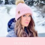 Woman wearing a pink knit hat with a pom-pom stands outdoors in a snowy landscape; text promotes a crochet pattern and video for the "Heavenly Herringbone Hat"—the perfect winter accessory to pair with your Snowy Season Sweater.