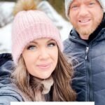 A woman in a pink knit hat with a brown pom-pom stands next to a man in a gray knit hat and jacket outdoors, both perfect for winter or pairing with the Snowy Season Sweater. Text: "Heavenly Herringbon Hat Crochet Pattern & Video.