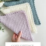 A hand holds three pastel Crochet Dishcloths in triangular shapes, with yarn skeins and greenery nearby. Text reads: "Cozy Cottage Dishcloth—Crochet Pattern & Video, Quick & Easy.