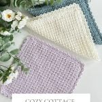 Three crochet dishcloths in pastel hues are displayed with green foliage, white flowers, and yarn balls. Text reads "Cozy Cottage Crochet Dishcloth Pattern & Video – Quick & Easy.