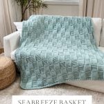 A light blue Basket Weave Blanket is draped over a white sofa in a bright living room with large windows and neutral decor.