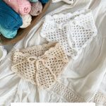 Two crocheted boho bandanas—one white, one beige—are displayed on a white fabric near a bowl of colorful yarn skeins and greenery. Text reads: "Caribbean Boho Bandana." The perfect crochet bandana for a laid-back, stylish look.