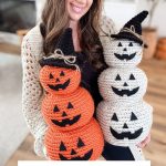 A woman holds two Crochet Jack-O-Lantern pumpkin stacks, one orange and one white, each with black hats and faces. Text below offers a free crochet pattern with video tutorial.
