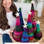 A woman holds a basket of colorful crocheted Holiday Trees, each topped with stars. Text reads: "Merry & Bright Christmas Trees Crochet Pattern & Video.