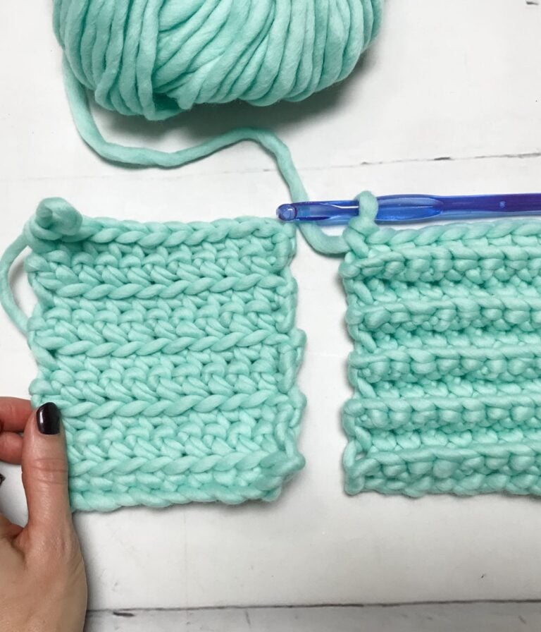 Two swatches of aqua chunky yarn crochet; one flat and one ribbed, with a large blue crochet hook and a ball of yarn in the background. A hand holds the flat swatch.