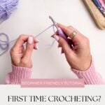 Hands crocheting with lavender yarn and a crochet hook, surrounded by tools and yarn on a white surface. Text reads: "First Time Crocheting? Learn the slip knot and chain stitch in this beginner friendly tutorial.