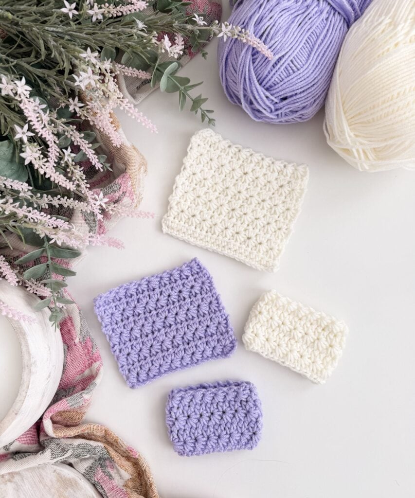 Four crocheted swatches in white and lavender yarn showcase the Crochet Star Stitch on a table beside yarn balls, flowers, and a scarf.