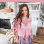 Woman wearing a pink crocheted poncho stands in a living room with fireplace and bookshelf; text overlays describe an easy summer crochet shell stitch poncho pattern, perfect for those searching for a free crochet poncho pattern.